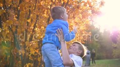 一个青少年和一个孩子玩，把他抱在怀里，吐出来。 太阳`阳光透过孩子。 他的笑声和欢乐